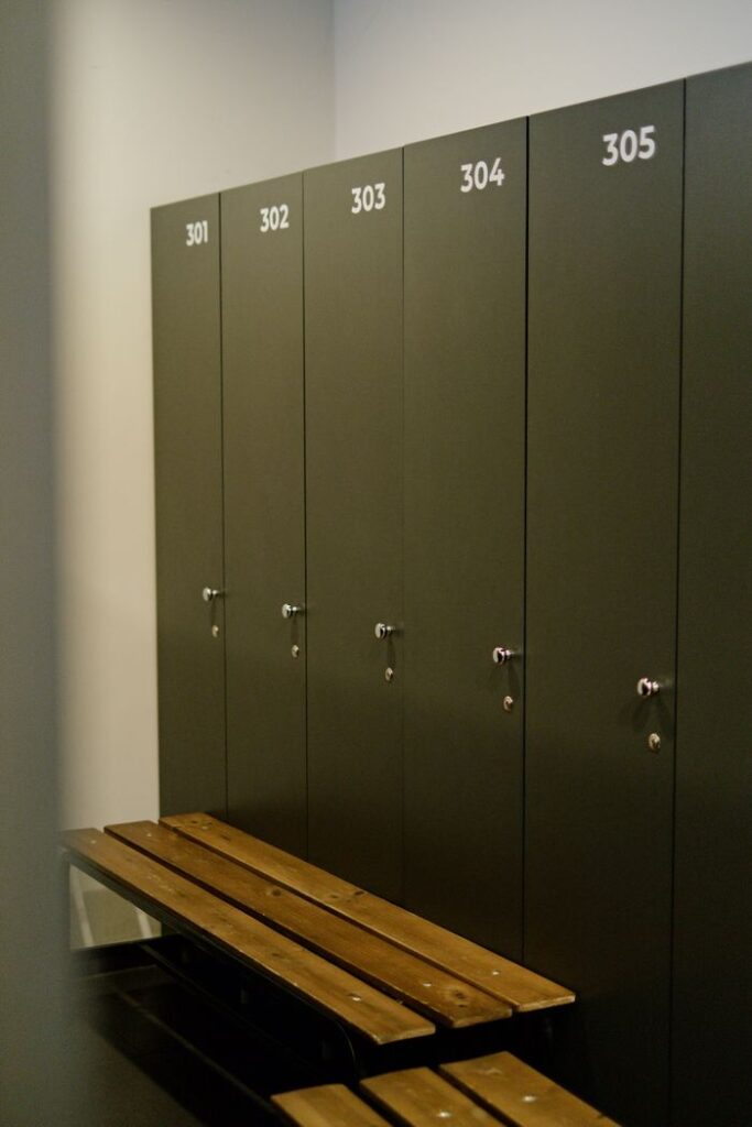 A clean and organized locker room with numbered lockers and a wooden bench.